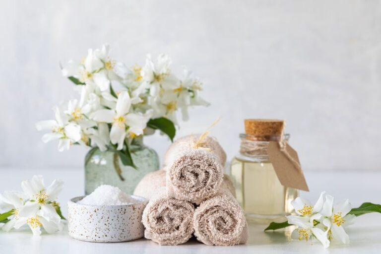Spa concept of jasmine oil, with bath salt and flowers on a white background. Spa and wellness still life. Copy space